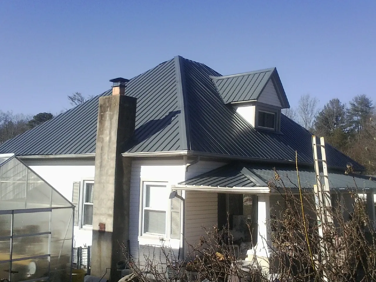 Dark blue standing seam metal roof on a white farmhouse with dormer — Slate & Tile Roof Repair by Roofing Brothers in Yelm