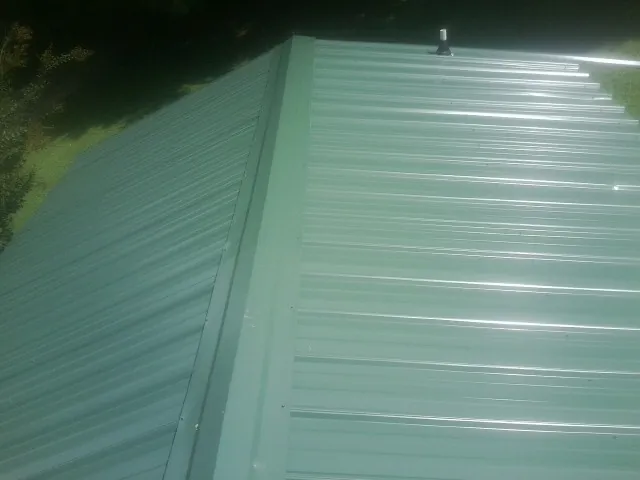 New green metal panels meeting at the ridge of a roof — Flat Roof Repair work by our crew in Yelm