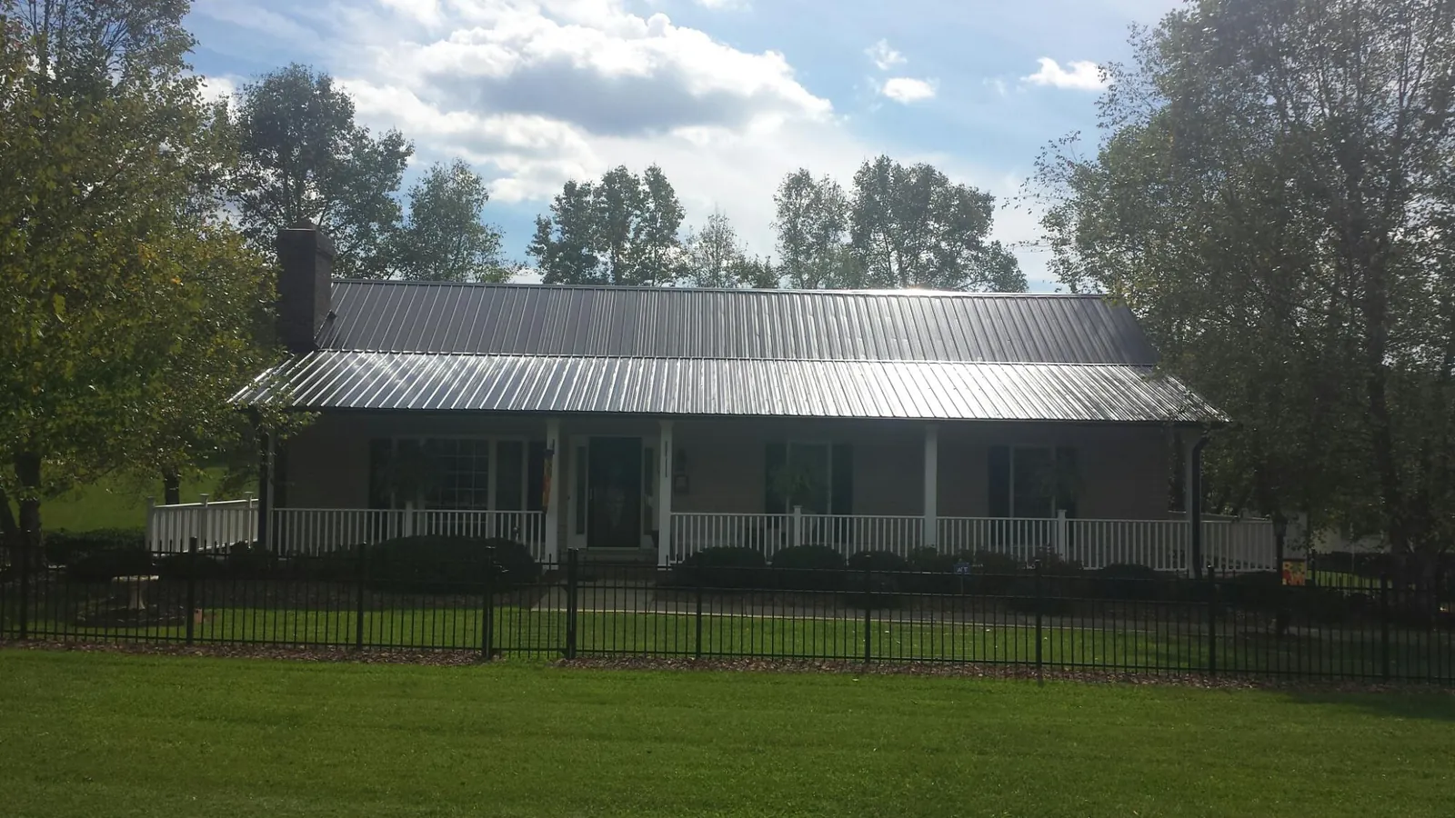 Gray metal roof on a brick ranch with a full width front porch — Gutter Guard Installation work by our crew in Yelm