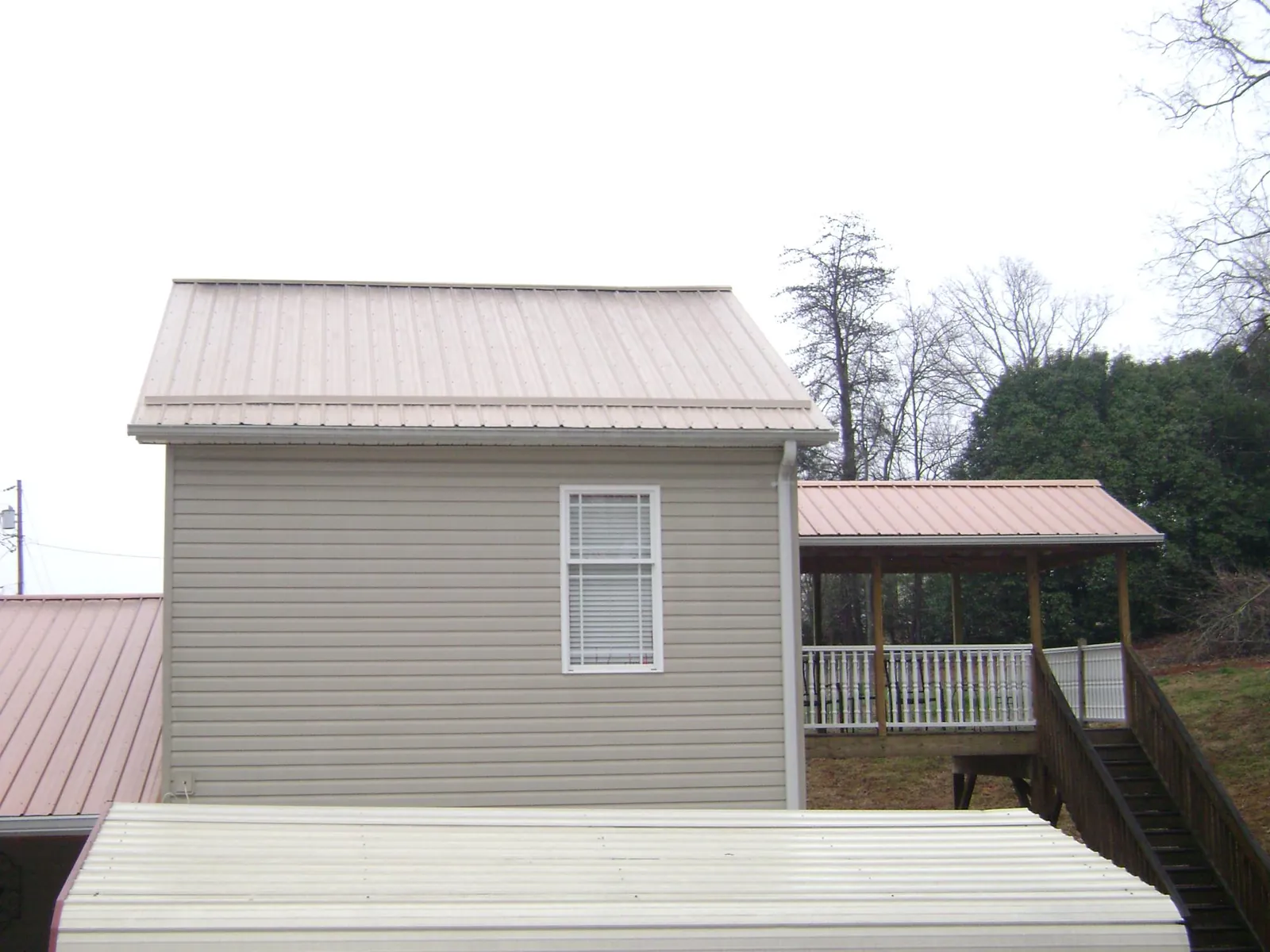 Tan metal roofs on a two story addition and attached porch, from a Roof Replacement job in Yelm
