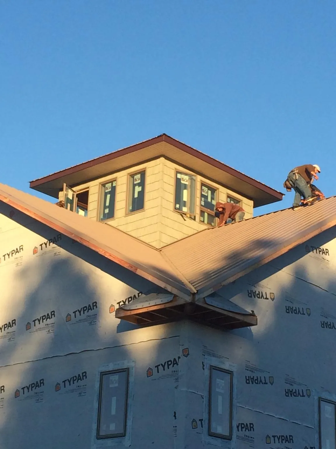 Roofers working around a rooftop cupola on a new metal roof at sunset — Roof Waterproofing in Yelm by Roofing Brothers